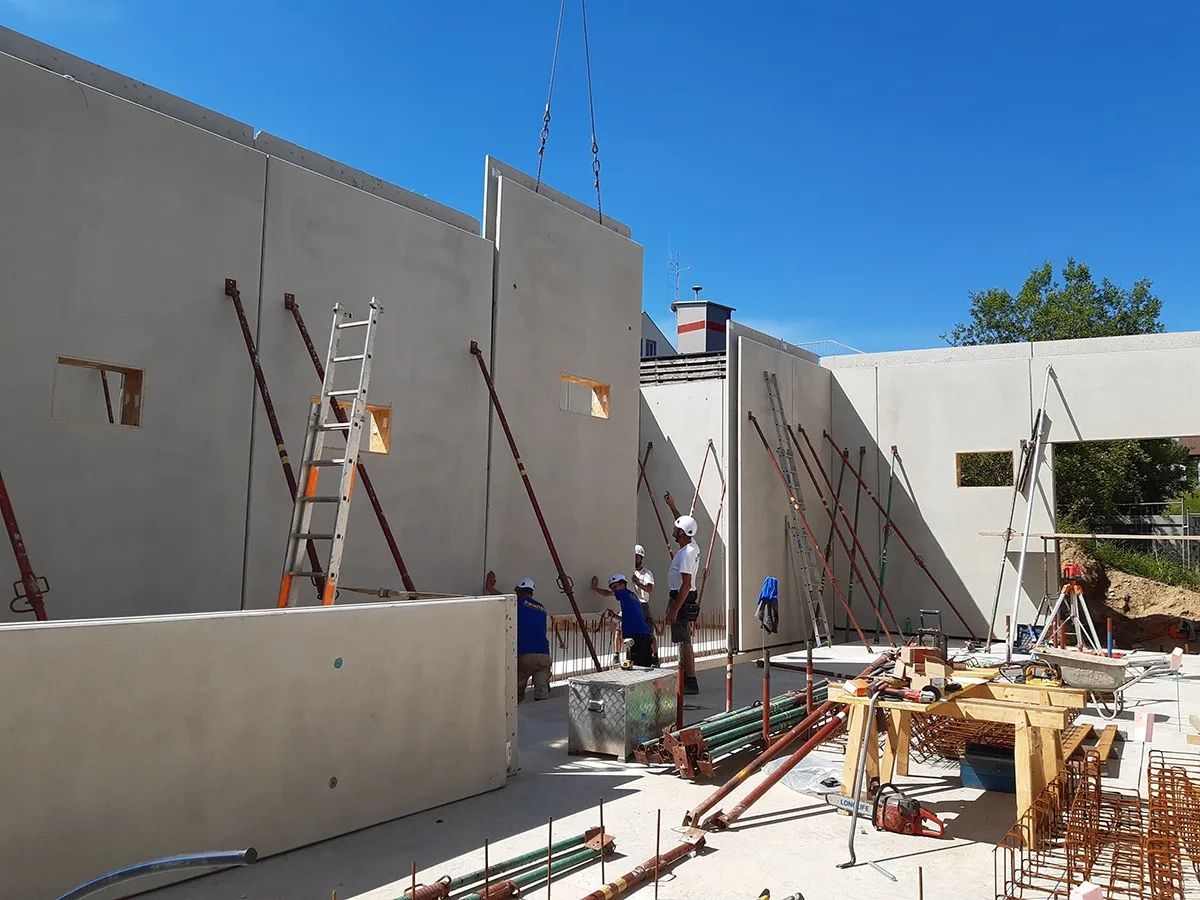 Montage von Wandelementen für eine Halle, Arbeiter an Stützen und Leitern